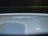 An aluminium coin floats on the surface of the water at 10&nbsp;°C. Any extra weight would drop the coin to the bottom.